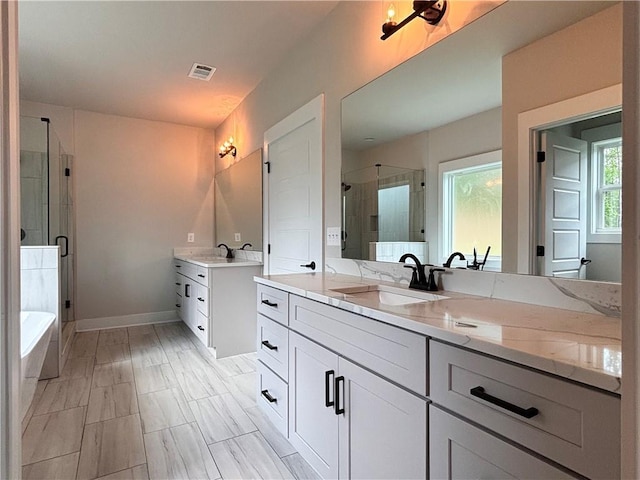 bathroom featuring baseboards, visible vents, a sink, a shower stall, and two vanities