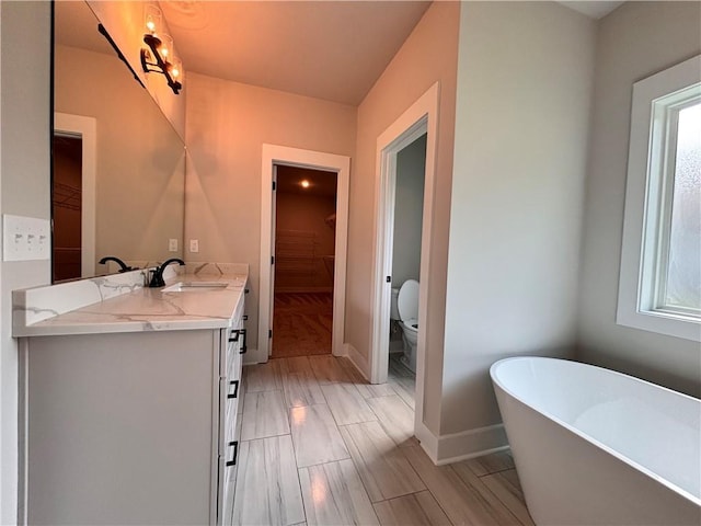 full bathroom with double vanity, a soaking tub, a sink, and a wealth of natural light