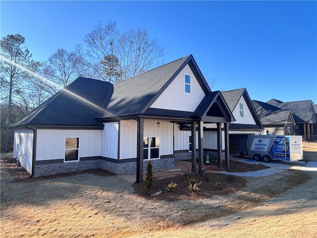 view of front of property featuring stone siding and a shingled roof