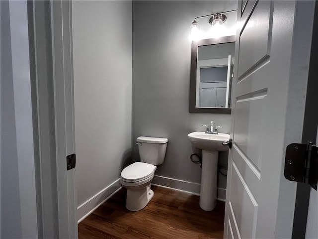 bathroom with a sink, wood finished floors, toilet, and baseboards