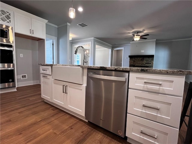 kitchen featuring visible vents, white cabinets, ornamental molding, dark stone countertops, and stainless steel appliances