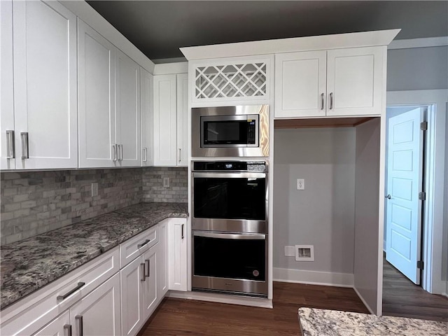 kitchen featuring dark wood finished floors, tasteful backsplash, appliances with stainless steel finishes, white cabinets, and light stone countertops