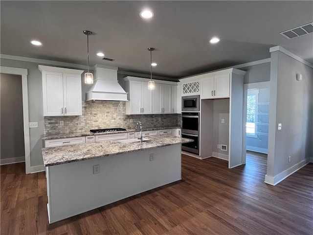 kitchen featuring stainless steel appliances, premium range hood, a sink, visible vents, and white cabinets