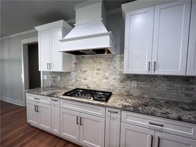 kitchen featuring dark wood-type flooring, premium range hood, stainless steel gas cooktop, and white cabinetry