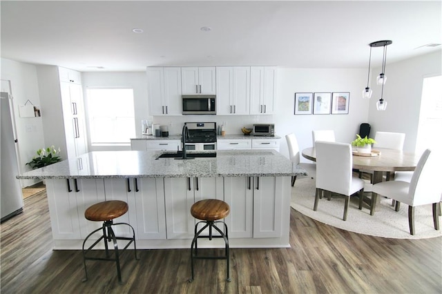 kitchen with appliances with stainless steel finishes, a sink, backsplash, and white cabinetry