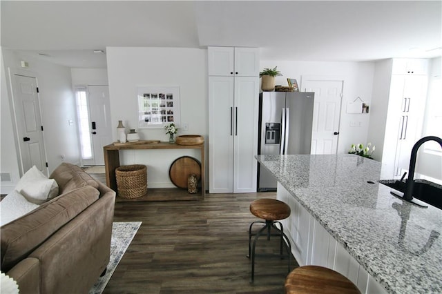 living room with healthy amount of natural light, wood finished floors, a fireplace with raised hearth, and baseboards