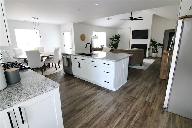 kitchen with stainless steel refrigerator with ice dispenser, dark wood finished floors, light stone countertops, a sink, and white cabinets