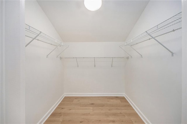 walk in closet featuring light wood-style floors and vaulted ceiling