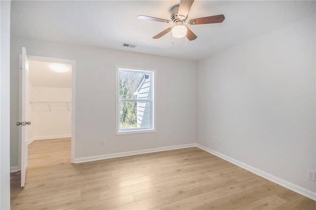 empty room with a ceiling fan, light wood-style floors, visible vents, and baseboards