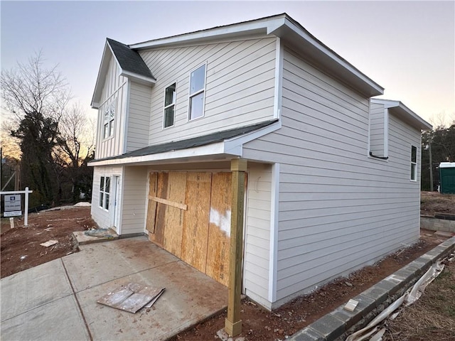 view of side of home with roof with shingles