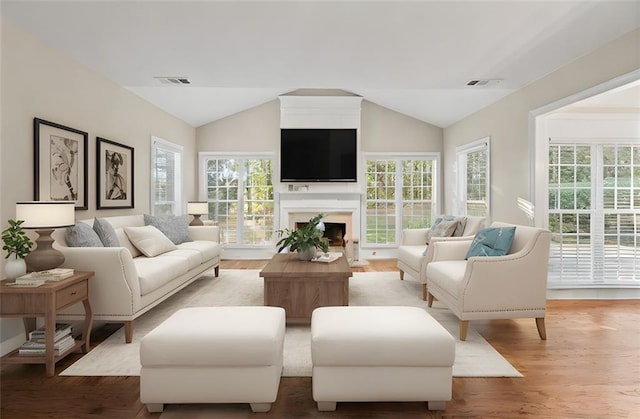 living area featuring lofted ceiling, visible vents, and wood finished floors