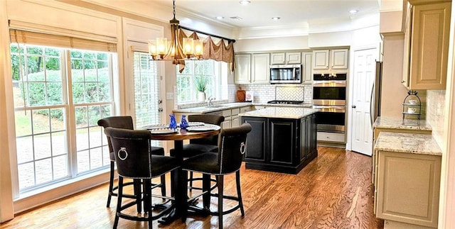 kitchen featuring light stone counters, stainless steel appliances, a center island, tasteful backsplash, and pendant lighting