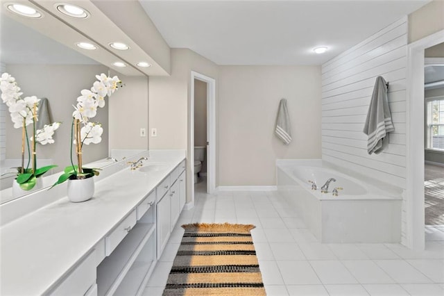 bathroom featuring tile patterned floors, toilet, vanity, baseboards, and a bath