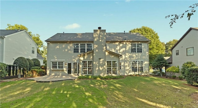 rear view of house featuring a chimney, a lawn, and a patio