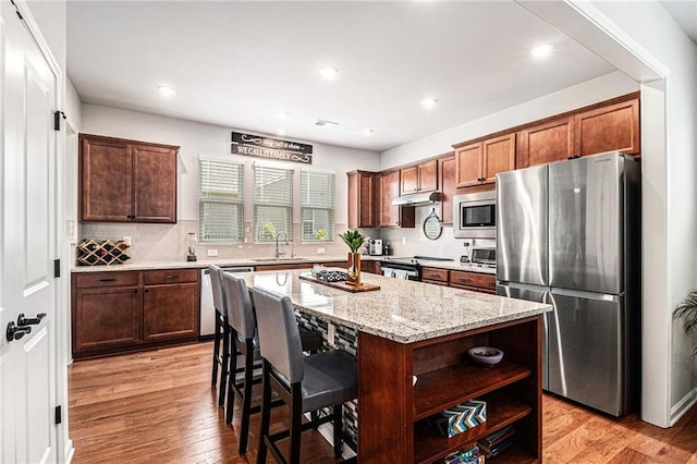 1000 Eight Knot Ct, Greensboro, GA 30642 - kitchen with stainless steel appliances, a sink, a kitchen island, light wood-type flooring, and light stone countertops