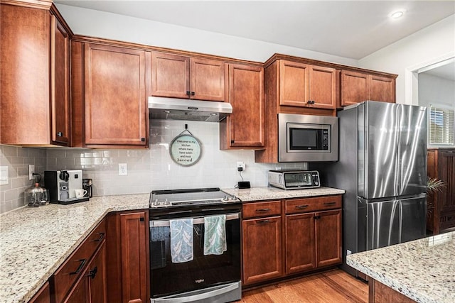 1000 Eight Knot Ct, Greensboro, GA 30642 - kitchen with appliances with stainless steel finishes, under cabinet range hood, light wood-type flooring, decorative backsplash, and light stone counters