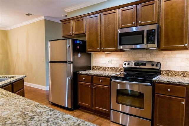 105 Maplecrest Ln, Rome, GA 30161 - kitchen featuring appliances with stainless steel finishes, wood finished floors, ornamental molding, decorative backsplash, and light stone counters