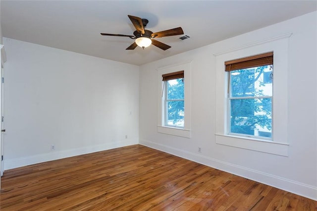 spare room featuring baseboards, a healthy amount of sunlight, and wood finished floors