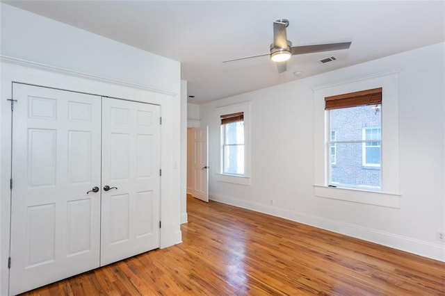 unfurnished bedroom featuring light wood-style flooring, a closet, baseboards, and visible vents