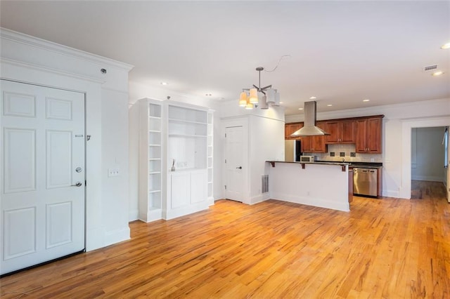 kitchen featuring a peninsula, stainless steel dishwasher, island exhaust hood, dark countertops, and an inviting chandelier