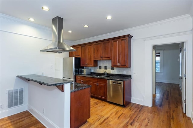 kitchen featuring crown molding, a peninsula, visible vents, stainless steel appliances, and island range hood