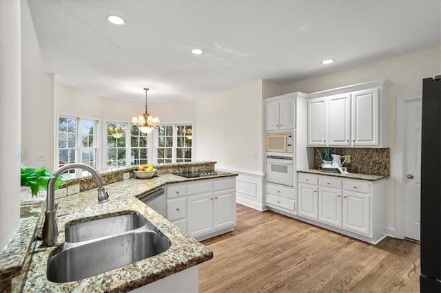 kitchen featuring white cabinetry, stainless steel appliances, light stone countertops, and sink