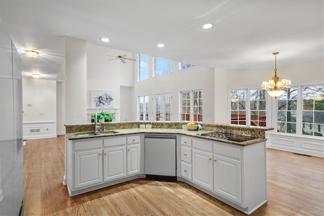 kitchen featuring stainless steel dishwasher, dark stone counters, sink, and white cabinets