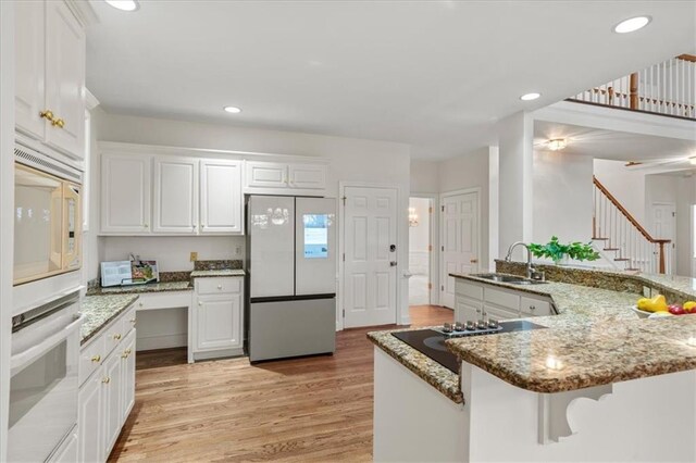 kitchen featuring sink, white cabinets, refrigerator, and kitchen peninsula