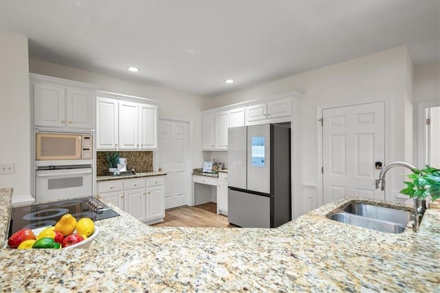 kitchen with tasteful backsplash, sink, white cabinets, and white appliances