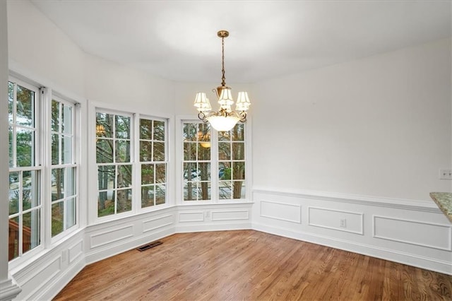 unfurnished dining area with an inviting chandelier and hardwood / wood-style floors