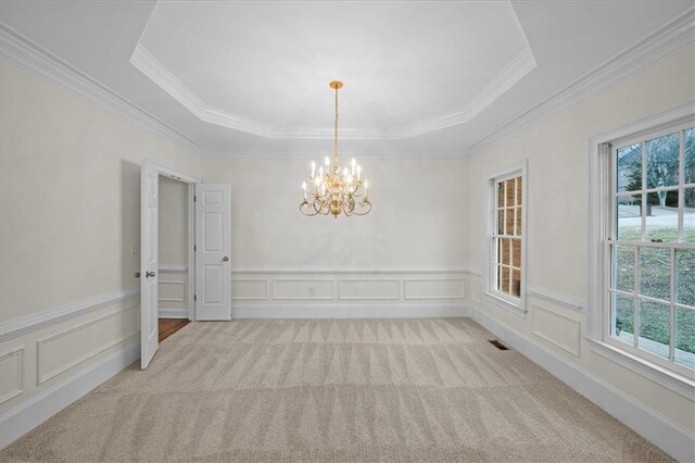 carpeted empty room featuring a chandelier, ornamental molding, and a raised ceiling