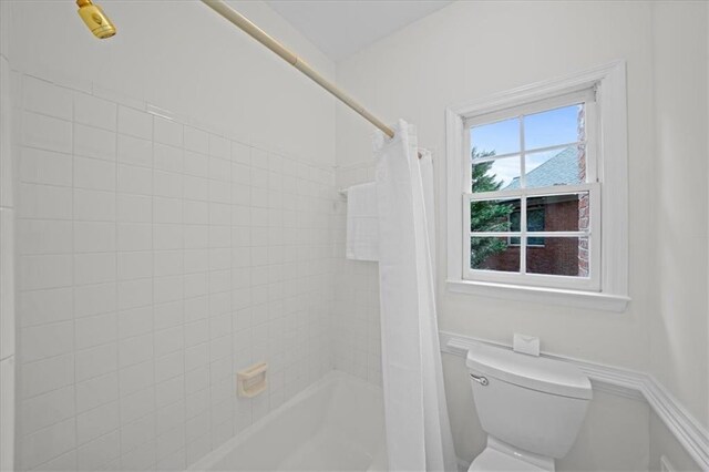 bathroom featuring shower / tub combo and toilet