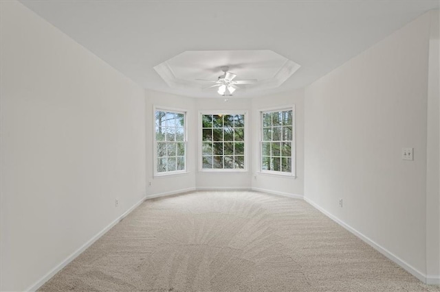 carpeted spare room featuring ceiling fan, plenty of natural light, and a raised ceiling