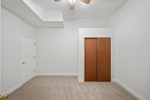 unfurnished bedroom with ceiling fan, light colored carpet, and a closet