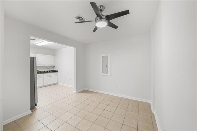 empty room with sink, electric panel, ceiling fan, and light tile patterned flooring