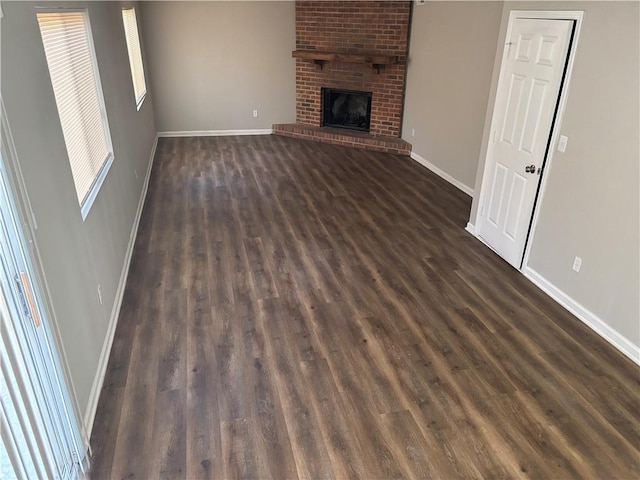 unfurnished living room with dark wood-style flooring, a fireplace, and baseboards