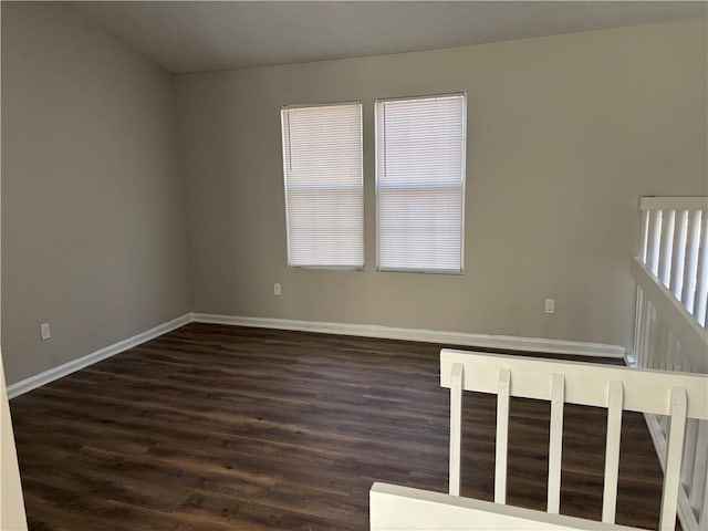 spare room with dark wood-style flooring and baseboards