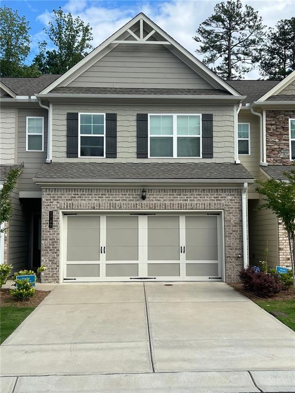 view of front of property featuring driveway, an attached garage, a shingled roof, and brick siding