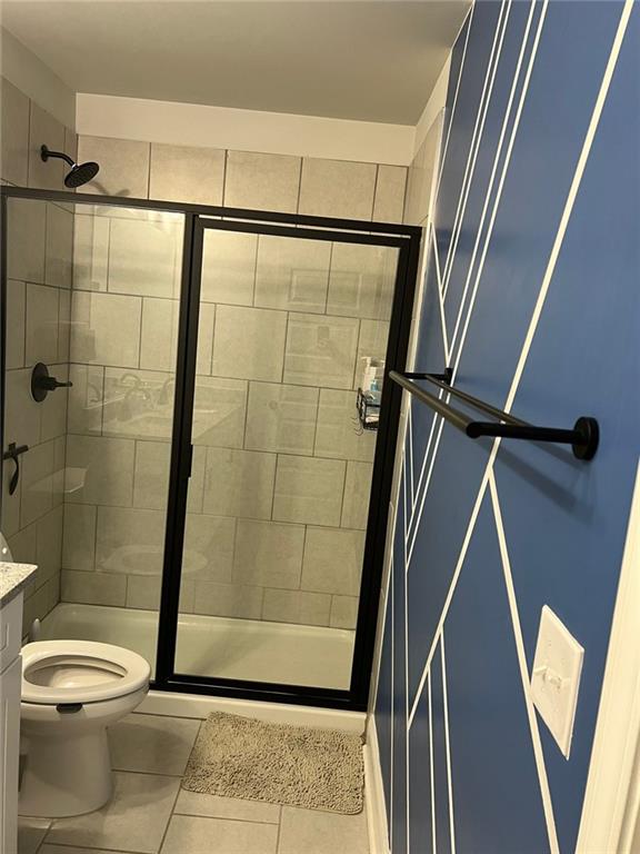full bath featuring tile patterned floors, a stall shower, toilet, and vanity