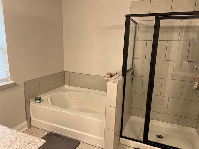 bathroom with tile patterned floors, a shower stall, a bath, and baseboards