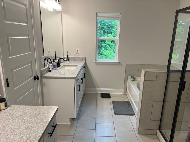 bathroom with vanity, tile patterned floors, baseboards, and a garden tub