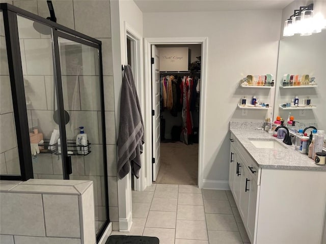 full bathroom featuring a stall shower, a spacious closet, vanity, baseboards, and tile patterned floors