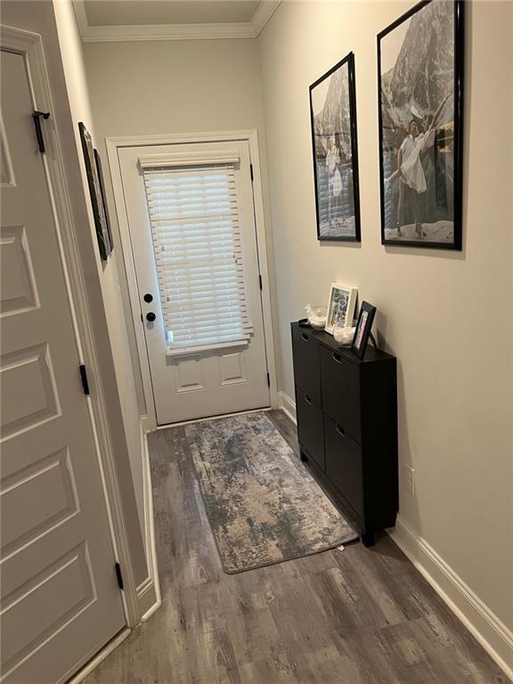 entryway featuring baseboards, wood finished floors, and ornamental molding