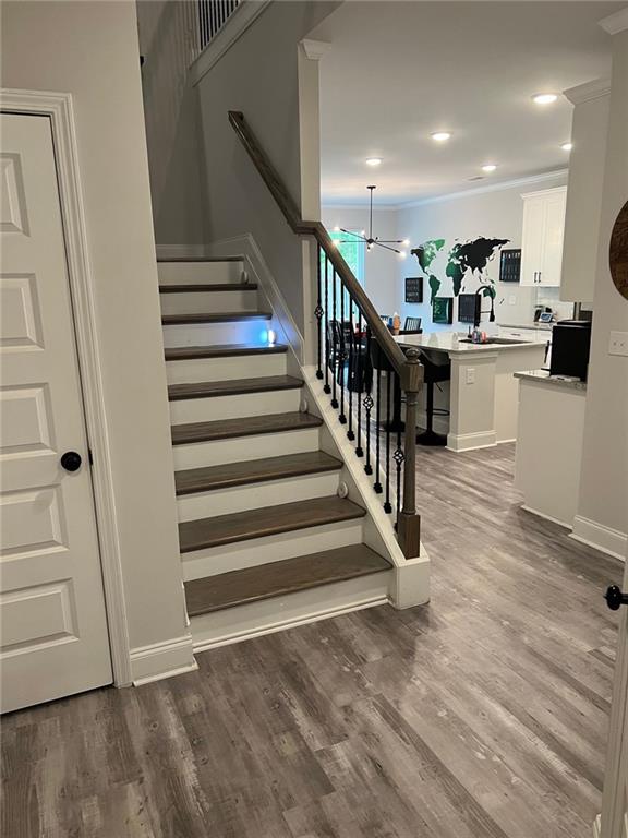 stairway featuring wood finished floors, a chandelier, baseboards, and recessed lighting