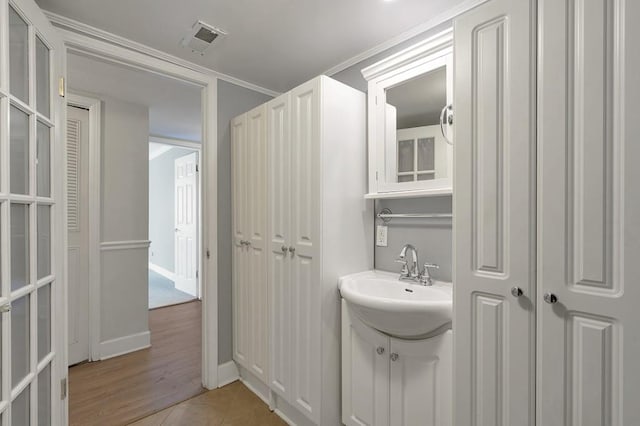 bathroom featuring tile patterned flooring, crown molding, and sink