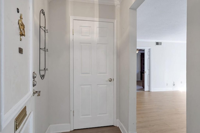 hall with light hardwood / wood-style flooring and ornamental molding