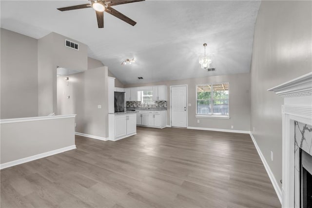 7262 Sandpiper Way, Riverdale, GA 30274 - unfurnished living room featuring a fireplace, vaulted ceiling, a ceiling fan, baseboards, and a chandelier