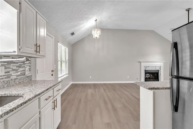 7262 Sandpiper Way, Riverdale, GA 30274 - kitchen with freestanding refrigerator, vaulted ceiling, light wood-style flooring, a high end fireplace, and decorative backsplash