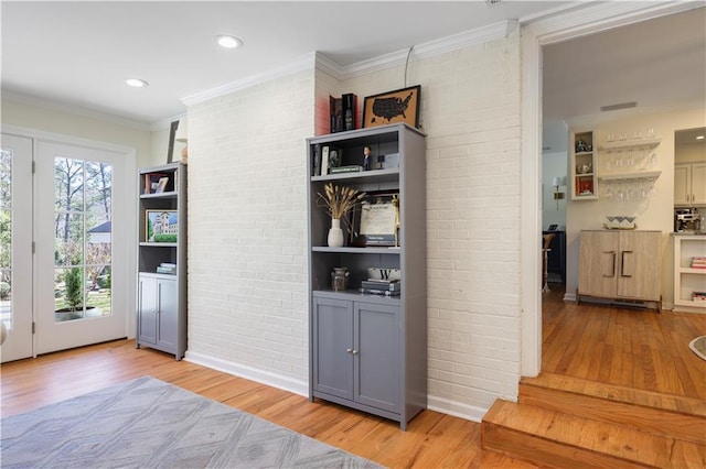 interior space featuring light wood finished floors, brick wall, ornamental molding, and recessed lighting