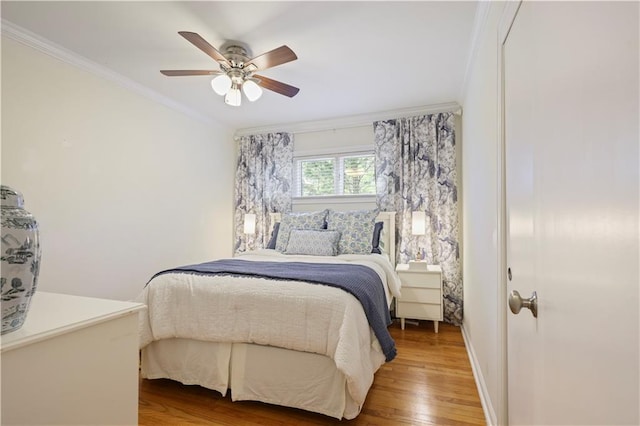 bedroom with ceiling fan, ornamental molding, and wood finished floors